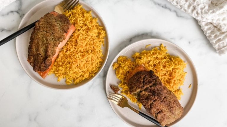 Overhead view of two white plates filled with Pesto-Coated Salmon and Rice Bowls