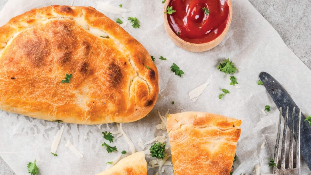 Overhead view of a Sausage and Pepper Calzone with marinara